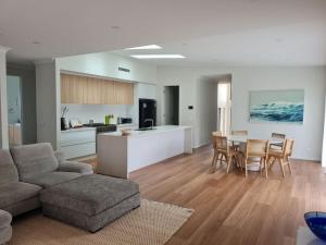 a living room and kitchen with a couch and a table at Songlark Street, 54 in Bermagui