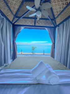 a bed in a tent with a view of the beach at The South Hideaway Oslob in Gawi
