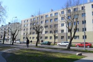 a person walking down a sidewalk in front of a building at Vītoli in Liepāja