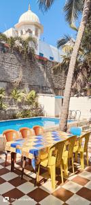 a yellow table and chairs next to a pool at Ocean Pearl Beach Villa & Retreat in Mahabalipuram