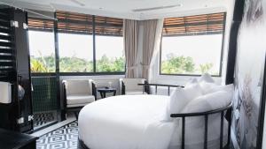a bedroom with a white bed and chairs and windows at The City Boutique Hotel in Bien Hoa