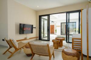 a living room with a tv and some chairs at Villa Le Blanc - Tropical Luxury 3BR Villa with Pool & Rooftop Views in Tumbak Bayuh in Tumbak Bayuh