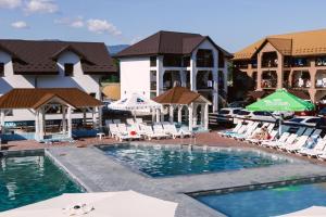 una piscina di fronte a un hotel con sedie e ombrelloni di Hotel BILYI AIST a Solotvino