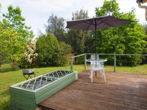 Domaine de l homme في Saint-Vincent-le-Paluel: طاولة ومظلة على سطح خشبي