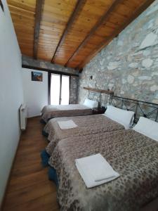 a row of four beds in a room with a stone wall at Casa Rural Borrenes las Médulas in Borrenes