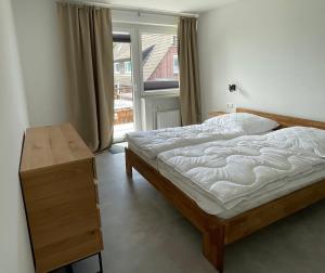 a bedroom with a bed and a table and a window at Ferienwohnung Brandung - Haus Seeschwalbe in Schillig