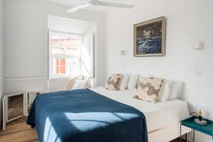 a white bedroom with a bed with a blue blanket at Central Ericeira Apartment with Lift in Ericeira