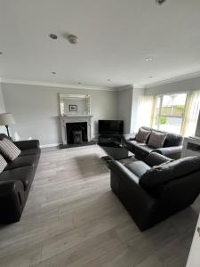 a living room with black couches and a fireplace at Castleshaw Holiday Home in Castlerock