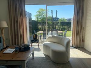 ein Wohnzimmer mit einem weißen Stuhl und einem Tisch in der Unterkunft Liguster 8 in Nieuwvliet
