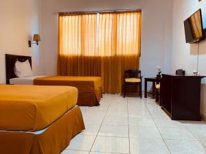 a hotel room with two beds and a television at Jati Hotel in Ternate