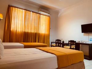 Una habitación de hotel con dos camas, un escritorio y una ventana. en Jati Hotel, en Ternate