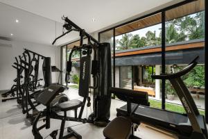 a gym with a row of treadmills and ellipticals at Villa Red Wine by BaliSuperHost in Ubud