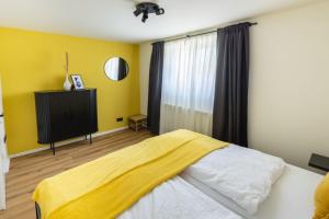 a bedroom with yellow walls and a bed and a television at Happy Place am Waldrand in Plettenberg
