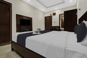 a bedroom with a large white bed and a television at Super Townhouse OAK HOTEL Heritage Heights in Jaipur