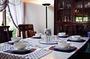 una mesa de comedor con platos y tazas. en Holidayhome Alam Cipanas Puncak, en Puncak