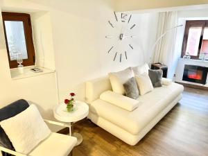 a living room with a white couch and a clock on the wall at La Casina de Cudillero in Cudillero