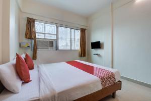 ein Schlafzimmer mit einem Bett mit roten Kissen und einem Fenster in der Unterkunft Hotel O Kamini in Pune