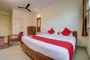 ein Schlafzimmer mit einem großen Bett mit roten Kissen in der Unterkunft Hotel O Kamini in Pune