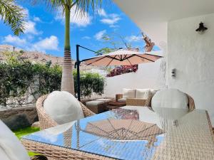 eine Terrasse mit einem Tisch, Stühlen und einer Palme in der Unterkunft Villa Nautica Puerto Rico by Alquiler de Súeño in Puerto Rico de Gran Canaria