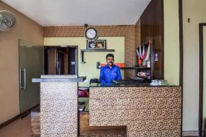 a man standing behind a counter in a room with a clock at Hotel O Hadoti Resort in Bhilwara