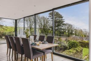 a dining room with a table and chairs and large windows at Little Redlap - Delightful views near Dartmouth in Dartmouth