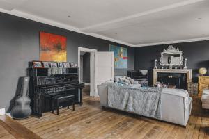 a living room with a couch and a piano at Little Redlap - Delightful views near Dartmouth in Dartmouth