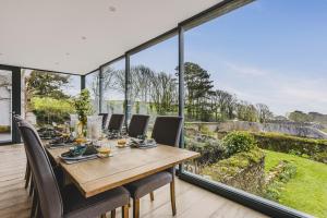 a dining room with a table and chairs and large windows at Little Redlap - Delightful views near Dartmouth in Dartmouth