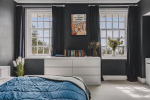 a bedroom with a bed and a dresser and windows at Little Redlap - Delightful views near Dartmouth in Dartmouth