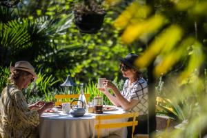 twee oudere vrouwen zitten aan een tafel met drankjes bij Maison Tournesol Massages Pau Jurançon in Gan