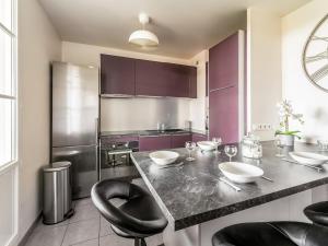 Una cocina con gabinetes morados y una mesa con sillas. en Appartement Le Petit Monde Magique, en Bailly-Romainvilliers