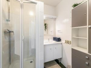 Un baño blanco con ducha y lavabo. en Appartement Le Petit Monde Magique, en Bailly-Romainvilliers