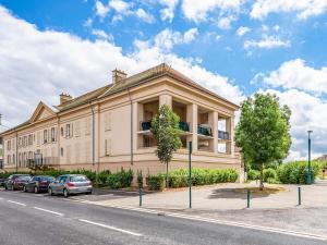 Un gran edificio con coches aparcados delante. en Appartement Le Petit Monde Magique, en Bailly-Romainvilliers