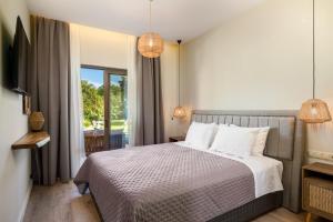 een slaapkamer met een bed en een groot raam bij Phos Elegant Residences by Konnect, 400m to the beach in Dassia +22 foto's