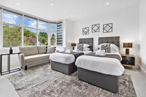 a white bedroom with two beds and a couch at Spacious 5BR for Work Crews Parking & WiFi in Luton