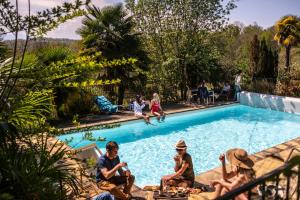 een groep mensen die rond een zwembad zitten bij Maison Tournesol Massages Pau Jurançon in Gan