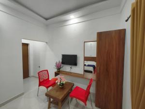 ChitradurgaSPR COMFORTs的客厅配有红色椅子、桌子和电视