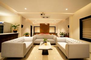 a living room with white couches and a table at SERENE WOODS in Srīkākulam