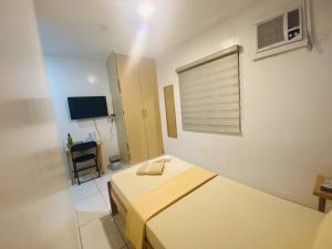 a small bedroom with two beds and a television at J Hotel in Roxas City