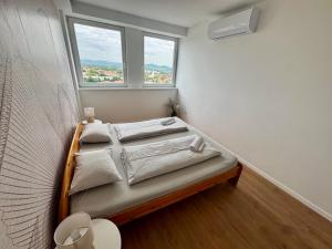 a small bed in a room with two windows at Panorama View Deluxe Apartment in Veszprém +5 photos
