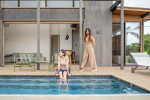 奄美Dei Amami的一名女子站在游泳池旁边，一名女孩站在旁边