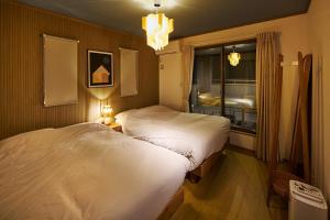 two beds in a hotel room with a window at Maigre A5 in Ito