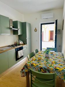 a kitchen with a table and chairs and a kitchen with green cabinets at Domus Apartament in Capo dʼOrlando +24 photos