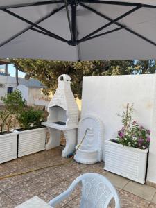 a white table and chair under an umbrella at Mina résidence A0 in Kelibia