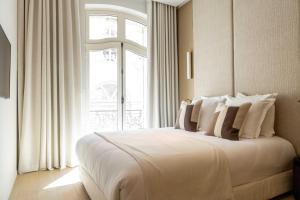 a white bed in a room with a window at Rive 15 - Appartements Parisiens in Paris