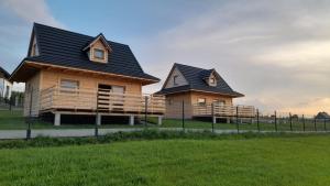 two houses in a field next to a fence at Domki na Bukowinie in Węgierska Górka