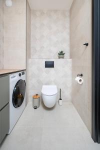 a bathroom with a toilet and a washing machine at Widzewska Chic Apartment by BookingHost in Łódź +14 photos