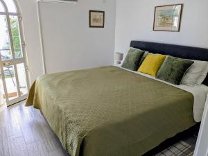 a bedroom with a green bed with yellow pillows at Tavira Garden Oasis in Tavira +28 photos