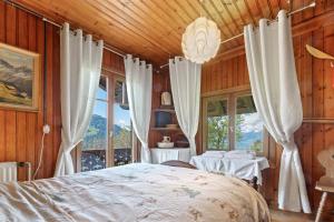 una camera da letto con un letto e una grande finestra di Grand chalet rustique à Gryon, avec vue et cheminée a Gryon