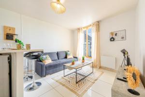 a living room with a blue couch and a table at Urban Oasis, RER D, CDG Aéroport, Parc des Expos in Gonesse