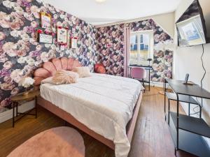 a bedroom with a bed with a floral wallpaper at La Parisienne Coquine Love and Plaisir - Love Room in Troyes +11 photos